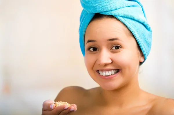 Pretty young healthy hispanic woman headshot with naked shoulders, blue towel wrapped around head, posing happily, creamy hands