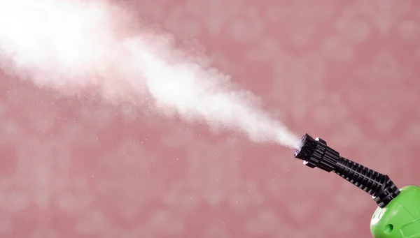 Closeup steam exiting nozzle of vapor cleaning machine, pink background