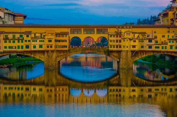 FLORENCE, ITALY - JUNE 12, 2015: The Old Bridge and Vasari Corridor in Florence, shops and turists on the middle of the Bridge. Shadow in the Arno river
