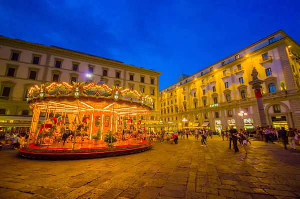 FLORENCE, ITALY - JUNE 12, 2015: Carousel at night iluminated in the middle of the square in Florence. Different forms waitting for childrens, people walking around