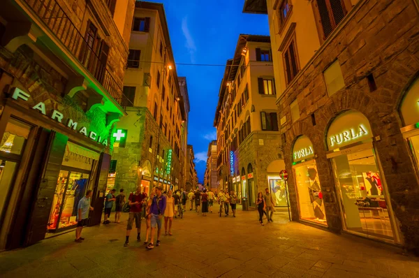 FLORENCE, ITALY - JUNE 12, 2015: Florence at night. Shops open late on summer, people visiting historical center, nice buildings with holding blue sky