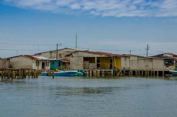 Muisne, Ecuador - March 16, 2016: Muisne town as seen from water, modest wooden houses sitting on poles waterfront pacific ocean, city buildings background and beautiful blue sky