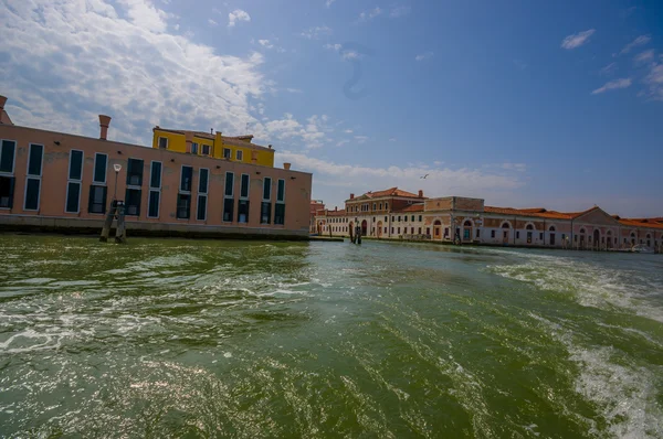 VENICE, ITALY - JUNE 18, 2015: Nice waves that a boat produces in the water of Venice, buildings far away