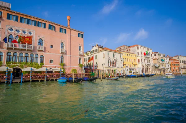 VENICE, ITALY - JUNE 18, 2015: Nice and pinturesque buildings in Venice, Italy flags on hotels. Little port to take water transportation