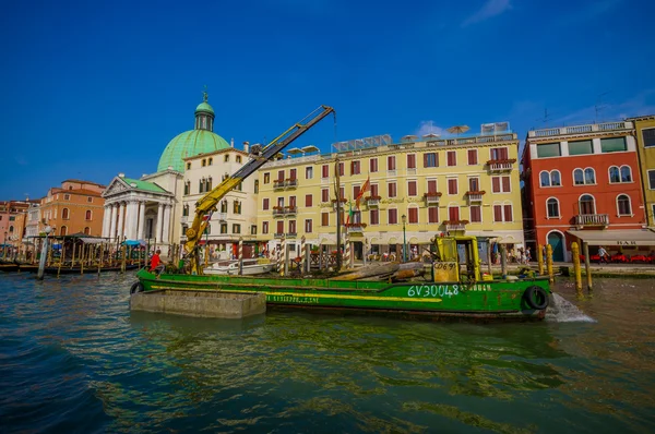 VENICE, ITALY - JUNE 18, 2015: Equipment with crane in Venice canals, machinery to help boats, behind green dome