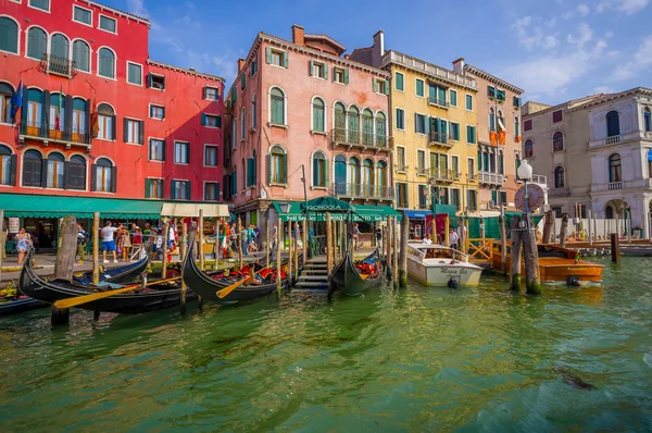 VENICE, ITALY - JUNE 18, 2015: Various gondolas and boats on the port in Venice street, commercial street. Restaurants and pinturesque color houses