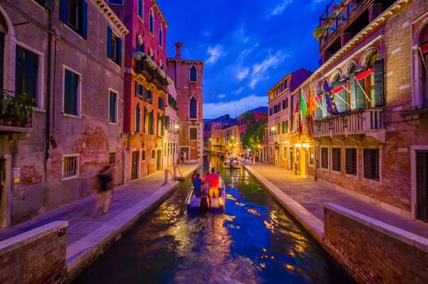 VENICE, ITALY - JUNE 18, 2015: Spectacular view of Venice at night, boat on the middle of canal. People visitting