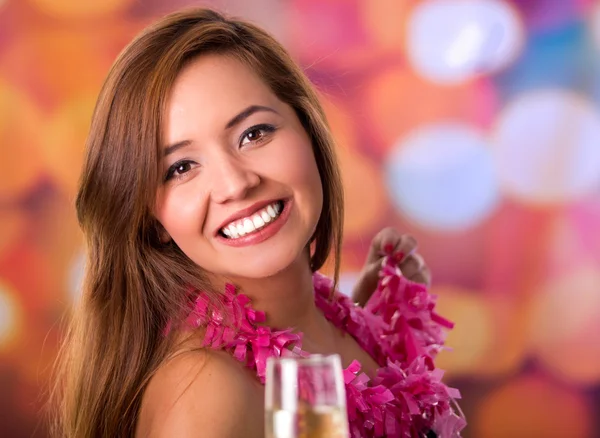 Very happy woman enjoying a party with a cup of champagne and pink party necklace, colored background