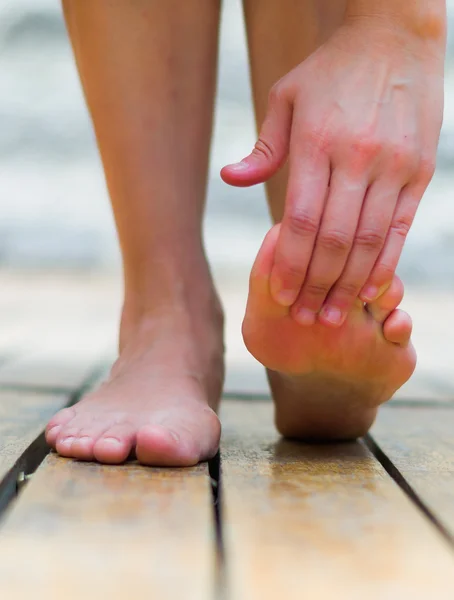 Massage foot when tiptoe hurts, woman making pressure on the fingers, wooden floor