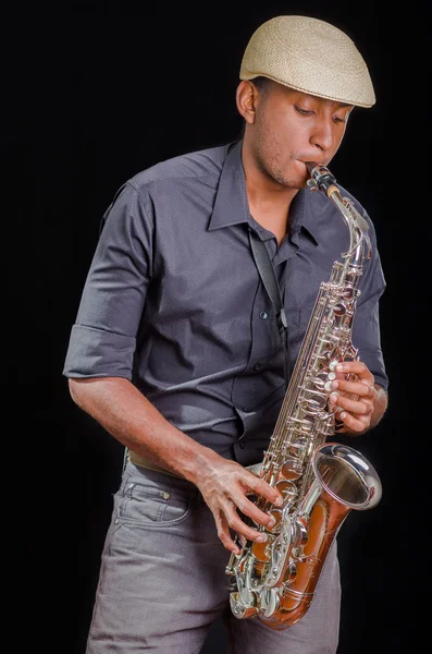 Black man playing the saxophone, feeling the music with white hat