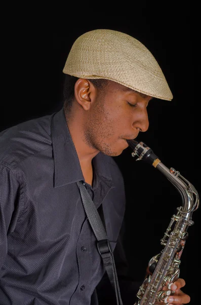 Close up of man with his saxophone, feel the song with closed eyes and white hat