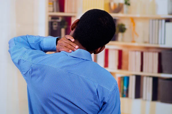 View from the back, man touching his neck with his hands. Pain signal