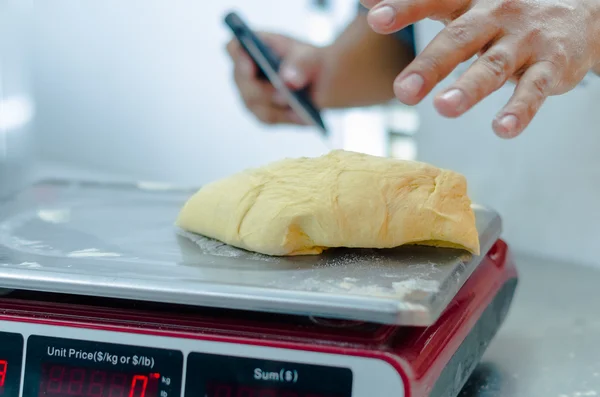 Bakers hands working and weighing bread dough on digital scale