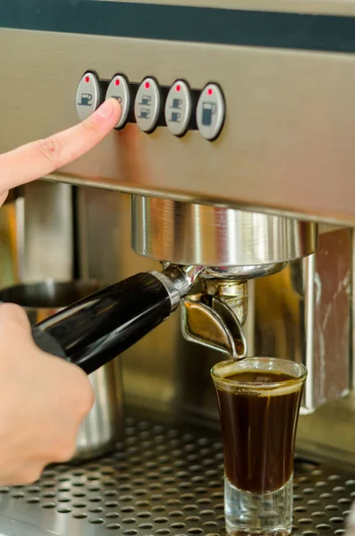 Female hands working operating industrial coffee maker, pouring espresso shot