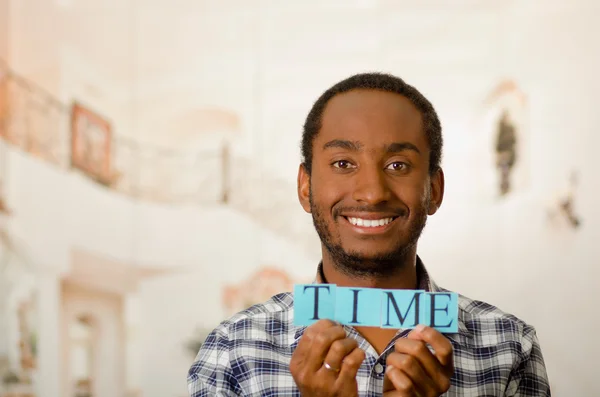 Headshot handsome man holding up small letters spelling the word time and smiling to camera