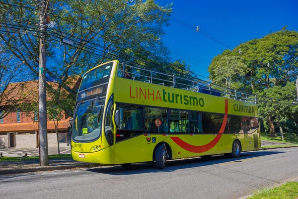 CURITIBA ,BRAZIL - MAY 12, 2016: green bus tour waiting on the stop parked in the street next to some trees