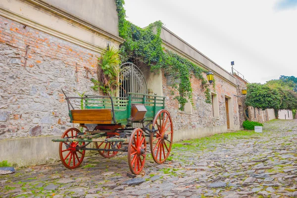 COLONIA DEL SACRAMENTO, URUGUAY - MAY 04, 2016: old green cart with red tires parked outside an ancient house
