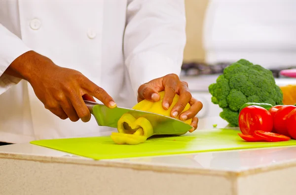 Closeup hands of chef cutting colorful vegetables in professional kitchen, white background