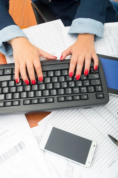 Closeup office womans fingers with red nailpolish writing on computer keyboard using both hands