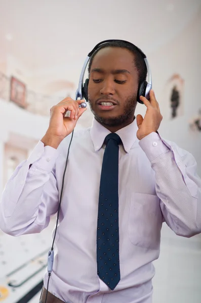 Handsome man wearing headphones with microphone, white striped shirt and tie, posing interacting working for camera