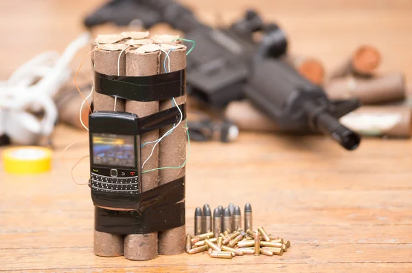 Homemade bomb with explosives and cellular phone attached wires sitting next to ammunition, machine gun in background