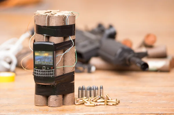 Homemade bomb with explosives and cellular phone attached wires sitting next to ammunition, machine gun in background