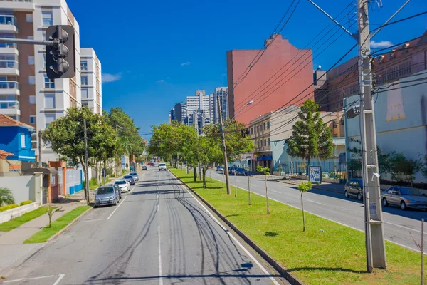CURITIBA ,BRAZIL - MAY 12, 2016: long empty street with some autos parked at the sides and some trees on the sidewalk