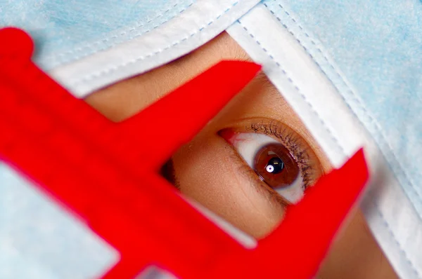 Closeup eye of woman peeking out from total facial cover, preparing for cosmetic surgery concept, doctor using red measure tool