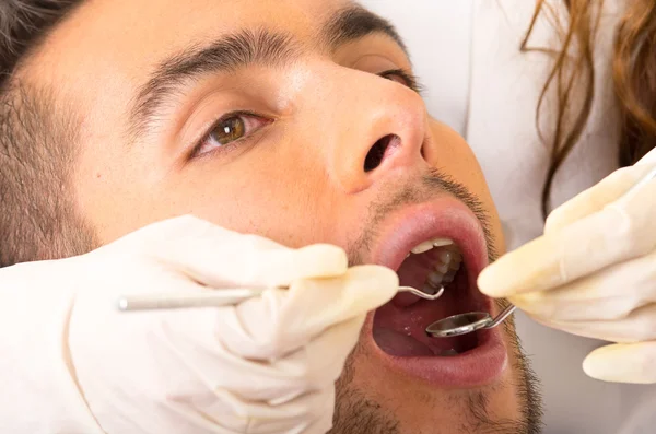 Closeup portrait of young handsome man at the dentist appointment