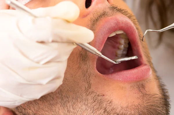 Closeup portrait of young handsome man at the dentist appointment