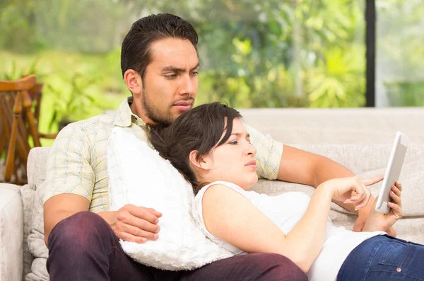 Young attractive couple relaxing in the sofa using tablet