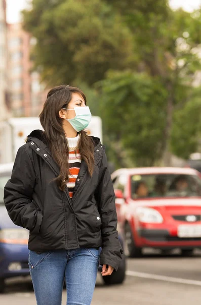 Young girl walking wearing a mask in the city street concept of pollution