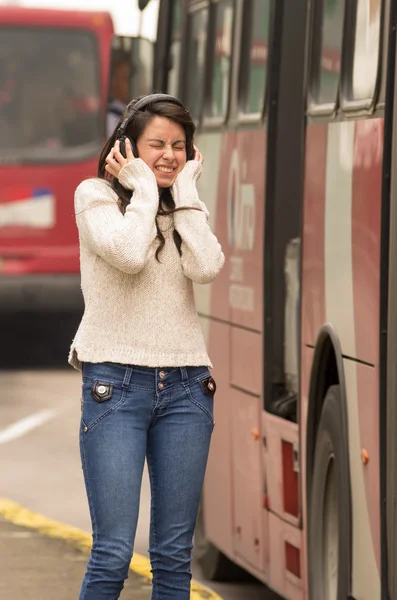 Woman walking on the city street covering her ears concept of noise pollution