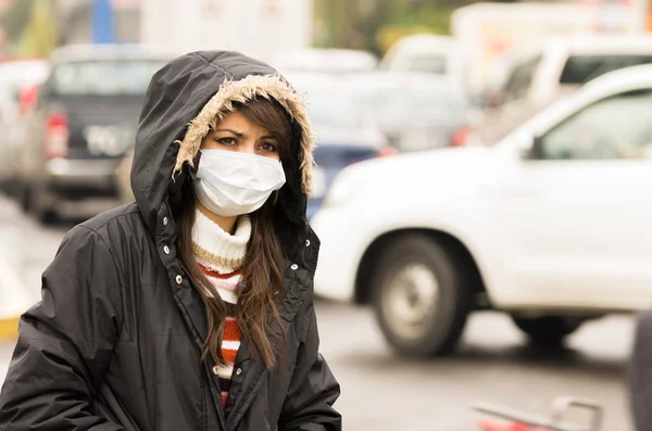 Young girl walking wearing jacket and a mask in the city street concept of  pollution