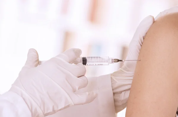 Closeup of doctors hand with injection holding patients shoulder