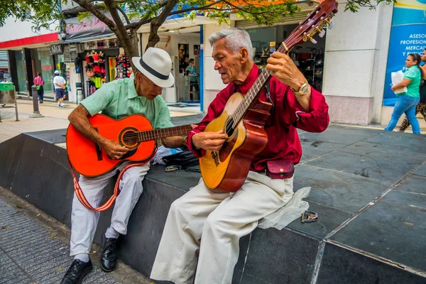 Two unidentify indigenous men playing guitar in the commercial street of Armenia, Colombia