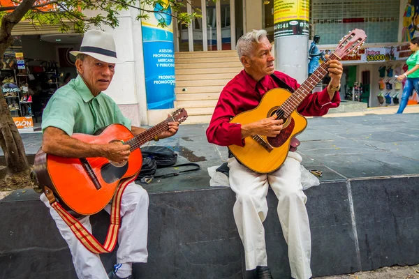 Two unidentify indigenous men playing guitar in the commercial street of Armenia, Colombia