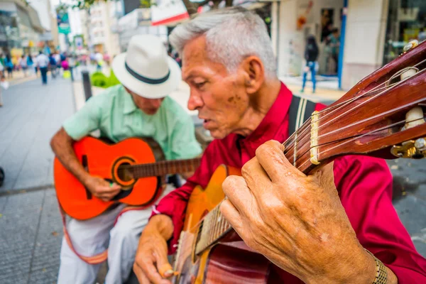 Two unidentify indigenous men playing guitar in the commercial street of Armenia, Colombia