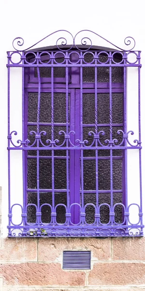 Purple colored window and metal bars on white concrete building