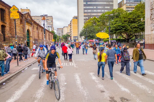 Unidentified hispanic pedestrians and cyclists moving through city street Candelaria area Bogota