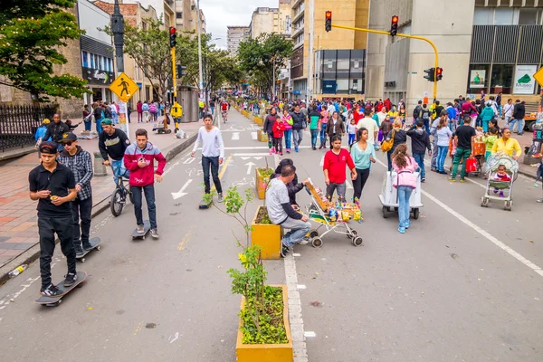Unidentified hispanic pedestrians, skateboarders and cyclists moving through city street Candelaria area Bogota