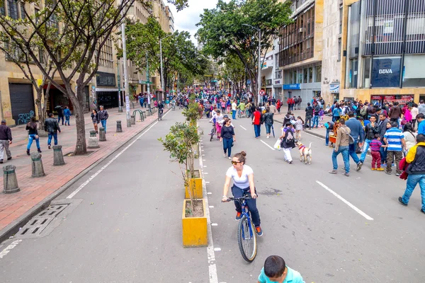 Unidentified hispanic pedestrians and cyclists moving through city street Candelaria area Bogota