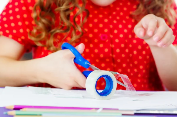 Little girl cutting adhesive tape