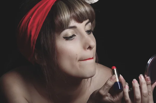 Portrait of cute young girl putting red lipstick on