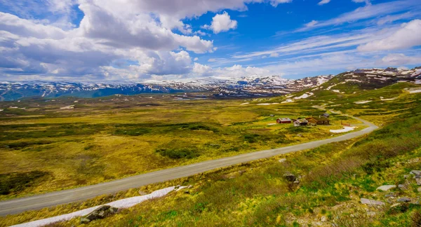 VALDRES, NORWAY - 6 JULY, 2015: Stunning nature on Valdresflya, green covered landscape stretches far as eye can see with spots of snow and lakes under beautiful blue sky
