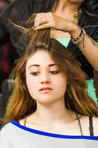 Brunette facing camera getting hair done by professional stylist