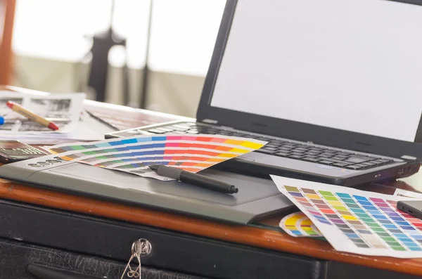 Laptop working desk with pantone palette, colormap lying on top of it