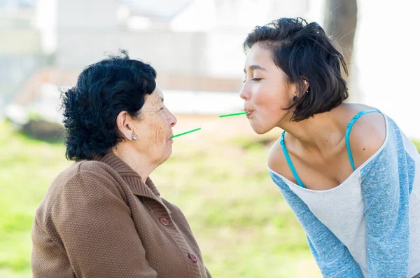 Lovely hispanic grandmother and granddaughter enjoying quality time outdoors sharing snacks