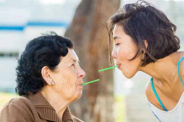 Closeup lovely hispanic grandmother and granddaughter enjoying quality time outdoors sharing snacks