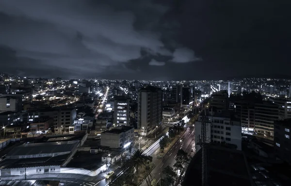 Cool photo of Quito at night showing parts of the city with lit up buildings skyline in a dark blue mystified light
